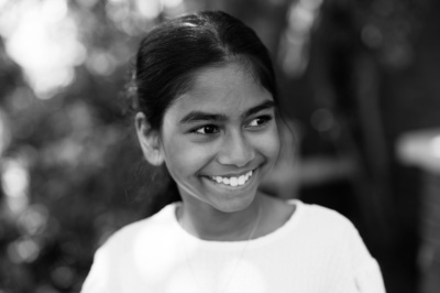 A black and white portrait of a smiling teenager.