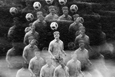 A teen heads a ball in a black and white portrait.