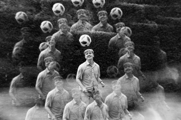 A teen heads a ball in a black and white portrait.