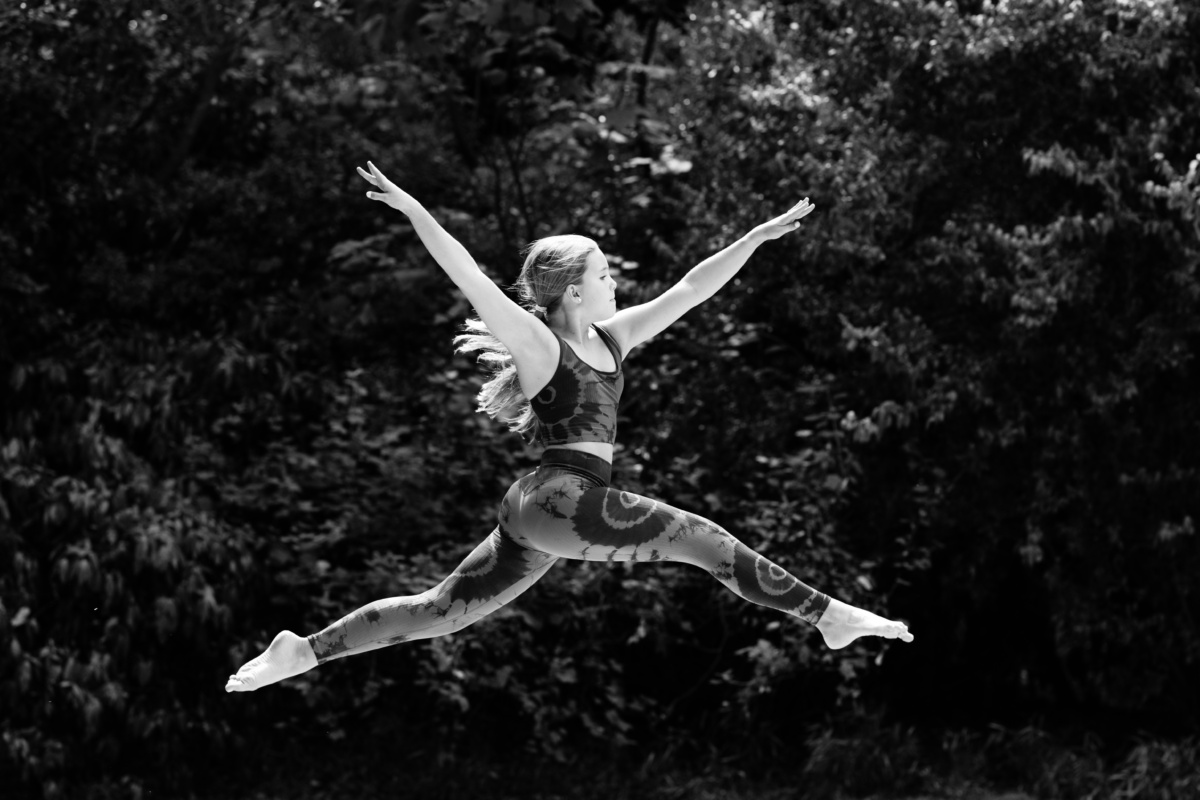 A teenager leaps into their air, with trees in the background.