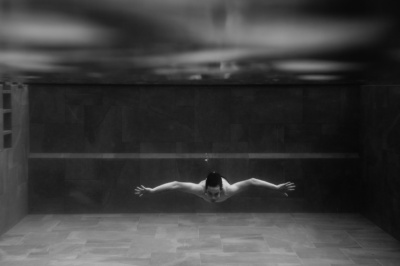 A teen swims underwater with a few bubbles rising towards the surface.