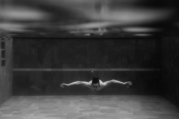 A teen swims underwater with a few bubbles rising towards the surface.