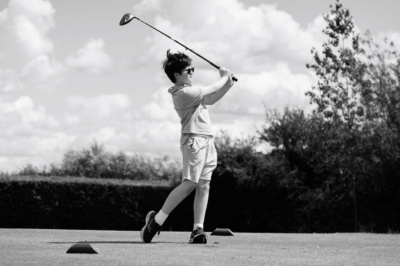 A teenager tees off on on a game of golf.