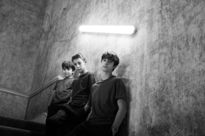 Teenage brothers in t-shirts against a concrete wall.