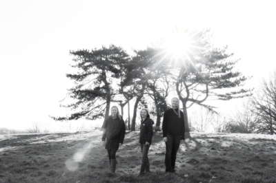 Teenagers stand together for a portrait with trees in the background.