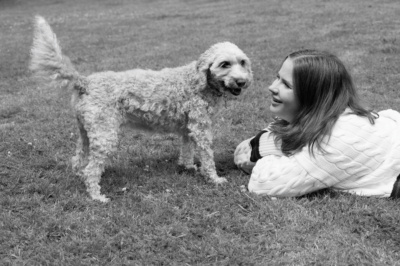 A teenager and her dog on a lawn.