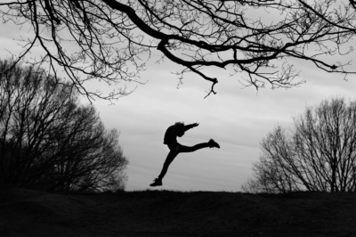 A teenager makes an athletic silhouette against the sky.