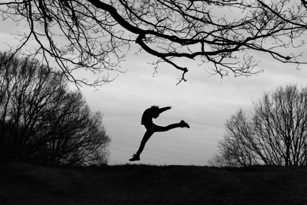 A teenager makes an athletic silhouette against the sky.