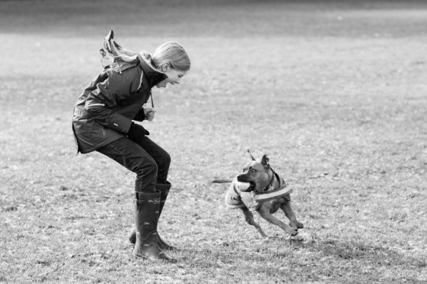 A teenage girl and her dog run across a field together.