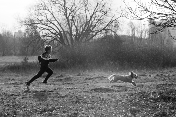 A teenage boy and his dog bound across a field in London.