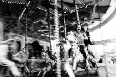 Teenagers laugh with delight on a merry-go-round horse.