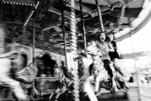 Teenagers laugh with delight on a merry-go-round horse.