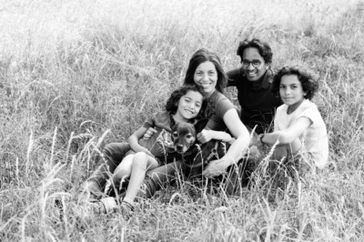 A family and their dog sit together in a field.