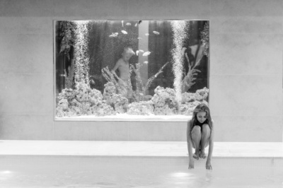 A teenager gets ready to jump into a pool with an aquarium in the background.