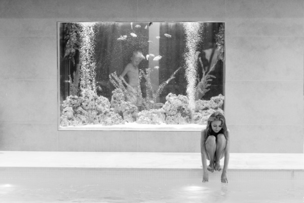 A teenager gets ready to jump into a pool with an aquarium in the background.