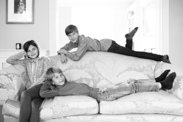 Three siblings drape themselves across a large sofa.