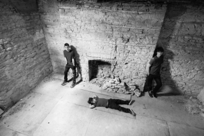 Three teenage brothers pose for a portrait in a brick room.