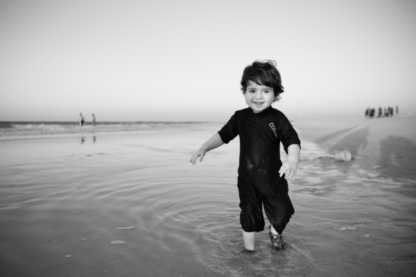 A toddler runs on the beach.