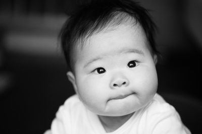 A tranquil baby looks into the light in this black and white portrait.