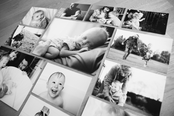 Black and white unframed prints sit on a wooden table.