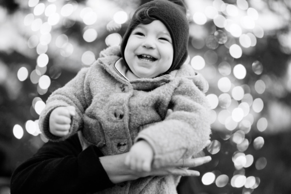 Parents hold up their baby in front of Christmas lights in London's Covent Garden while on vacation.