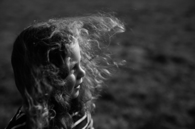 Wind blows a child's hair in a field.