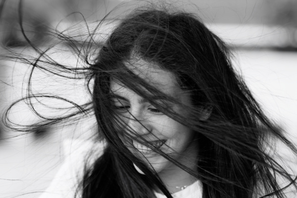 A windswept teen smiles during a family portrait shoot.