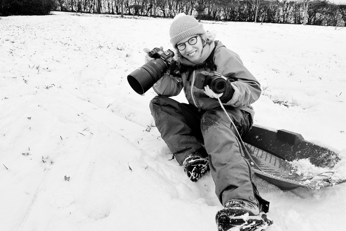 photographer Helen Bartlett on a sledge holding two Canon EOS R5 cameras