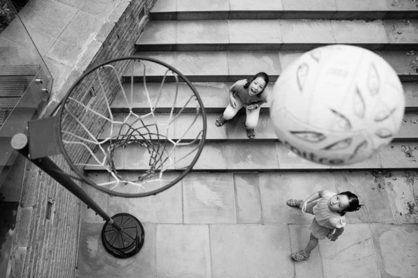 family photograph taken from above with two girls playing netball. The ball and the net are in the foreground with the girls below and behind.