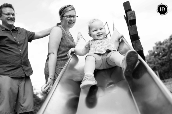 little-girl-plays-slide-while-parents-look-on-smiling