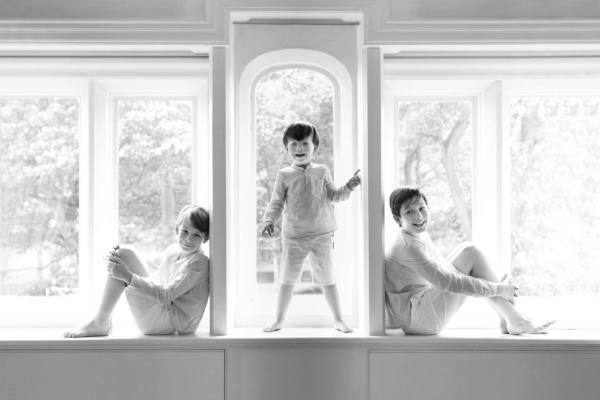 Three brothers pose for a family portrait in symmetrical window frames.