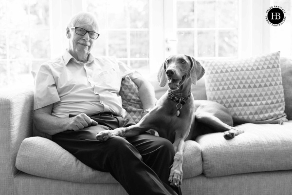 older-gentleman-sits-on-sofa-with-dog