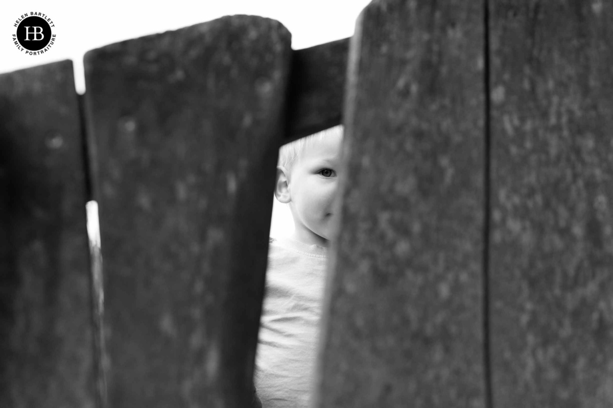 little-boy-peeks-through-gap-fence