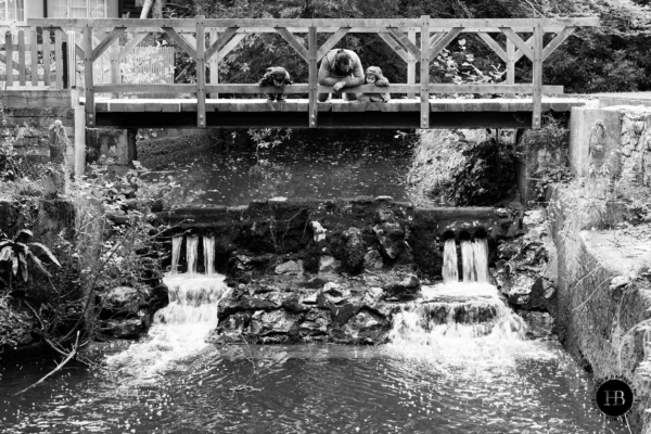 family-looks-at-river-from-bridge