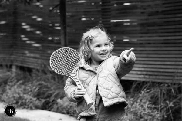 little-girl-plays-tennis-in-garden-on-rainy-photography-session