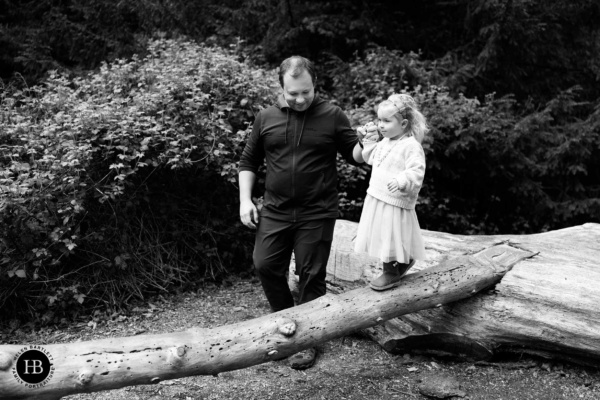 father-helps-daughter-balance-on-log