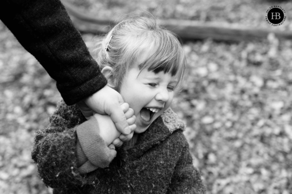 little-girl-laughs-while-holding-parents-hand