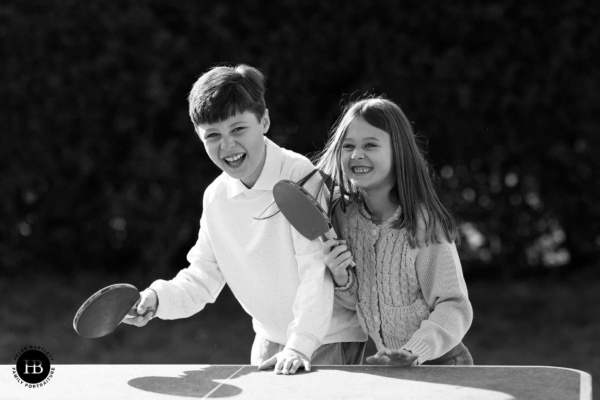 two-children-laugh-playing-table-tennis-on-family-photo-shoot-sw4