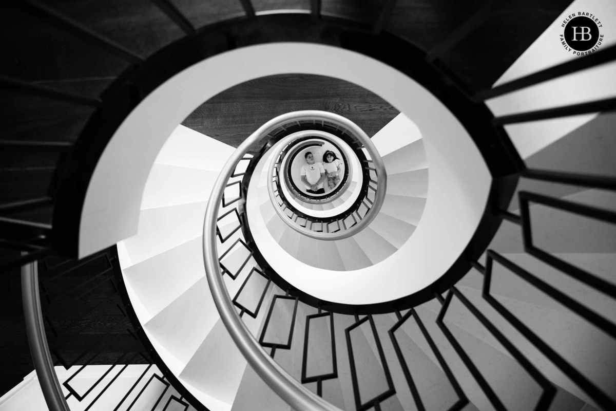 Two children framed at the centre of a sweeping spiral staircase, viewed from above by Helen Bartlett - family photographer Chelsea