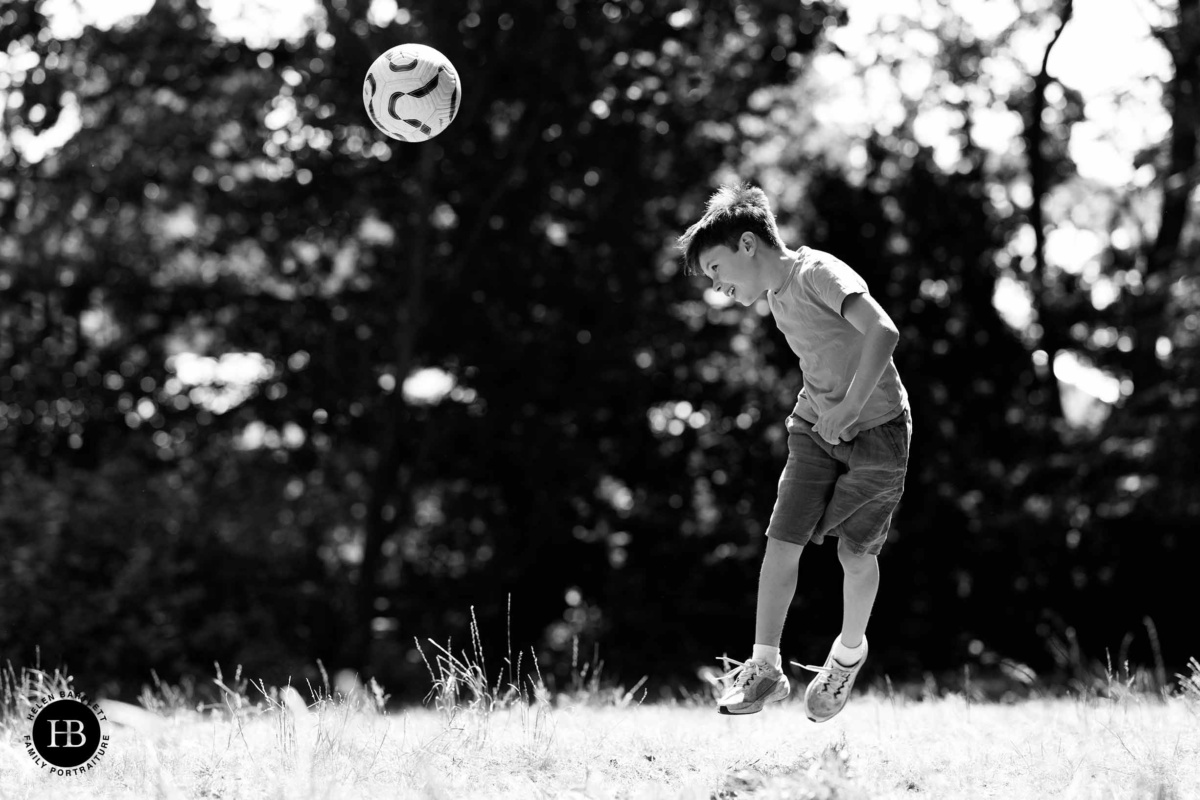 Boy watching a football float through the air during a game in Holland Park.