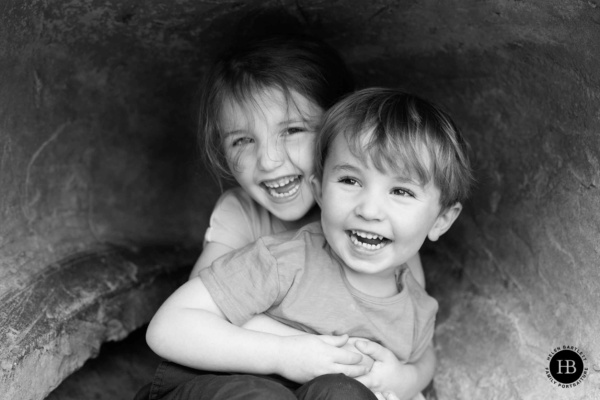 Brother and sister laughing together during family photography in Crystal Palace Park