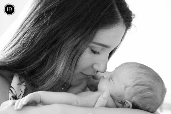 Mother holding newborn close during at home session in Islington