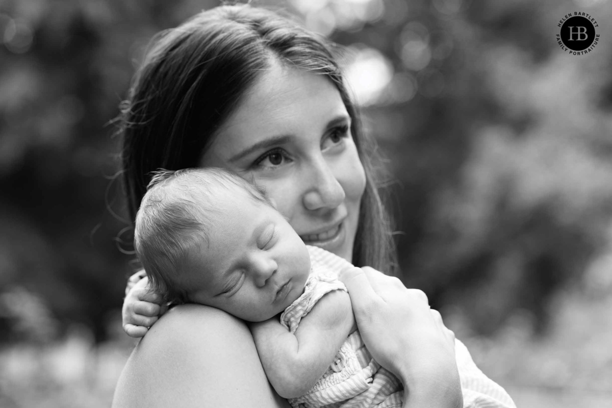 Newborn baby resting on mother’s shoulder outdoors in Islington