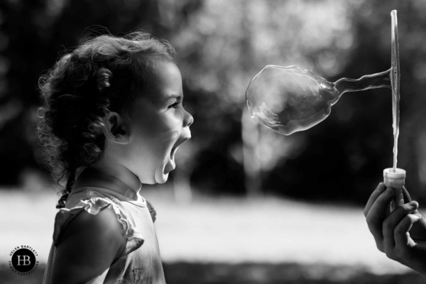 Little girl plays with bubble in dramatic light. Taken with Canon EOS R6 Mark III camera