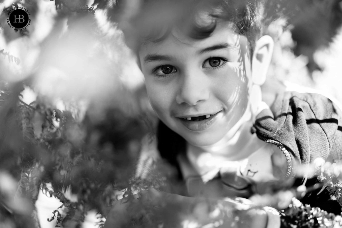 Close-up portrait of a child looking through leaves in woodland