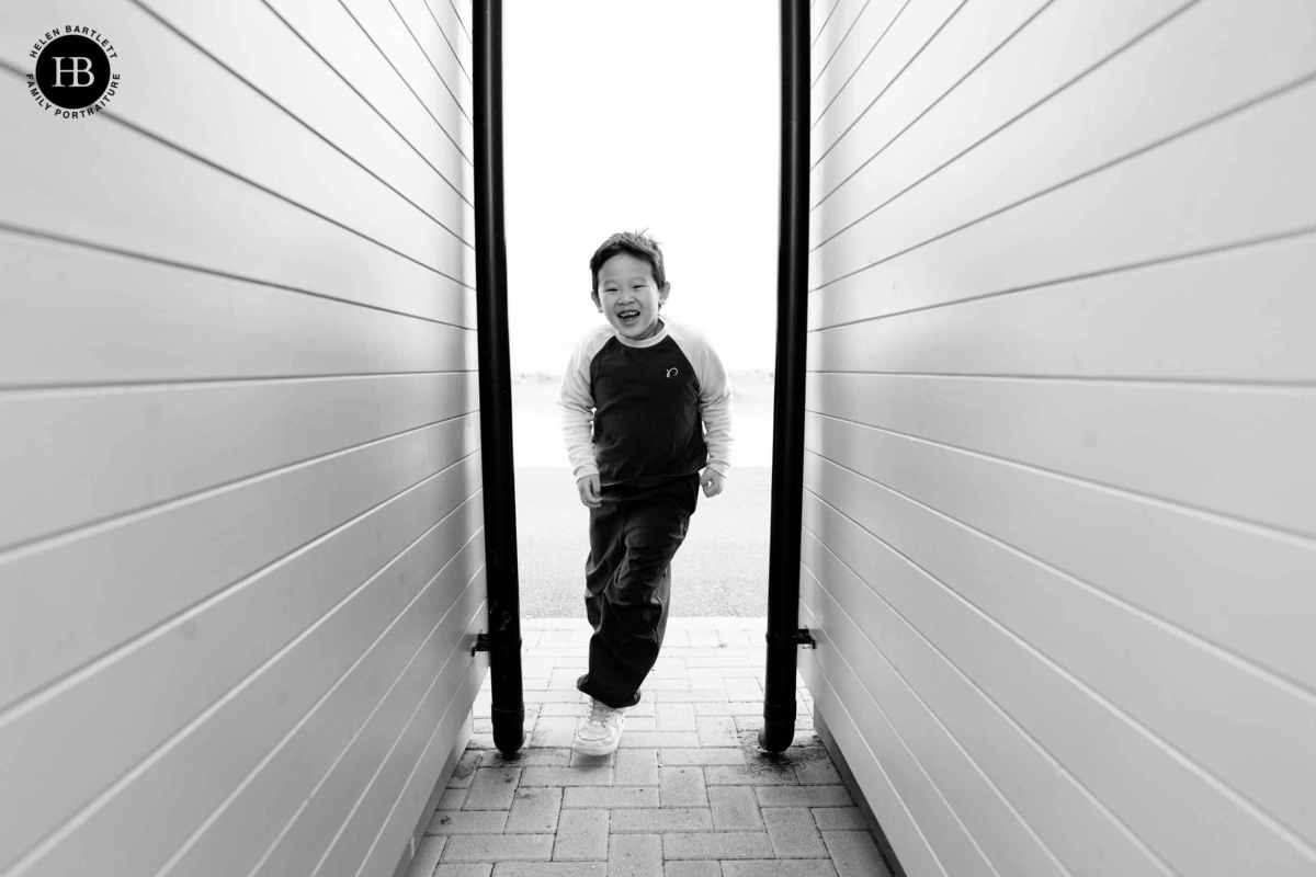 Child running between beach huts toward the beach