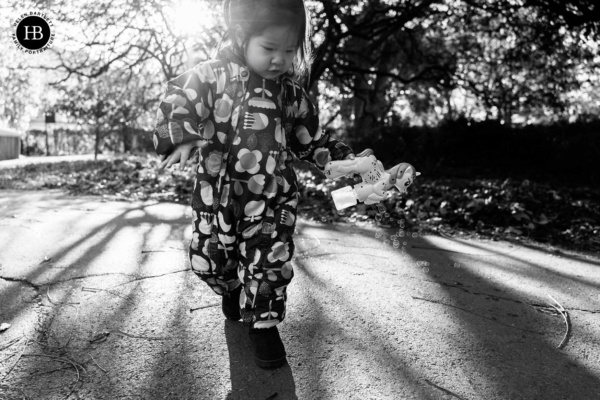 Young child holding a bubble toy outdoors during a family photo shoot in winter light in Fitzrovia