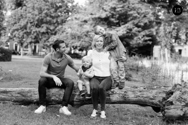 Family sitting together on a fallen tree in a green garden square