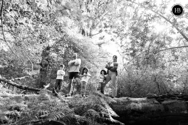 Family standing together on a fallen tree in woodland