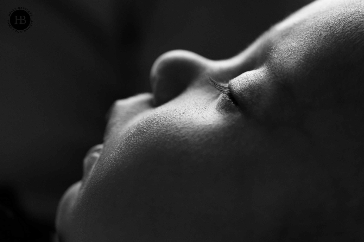 Side profile of a sleeping newborn baby photographed in black and white